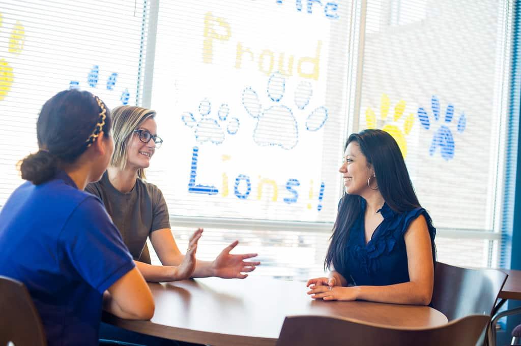 Students sitting down at a table having a conversation.