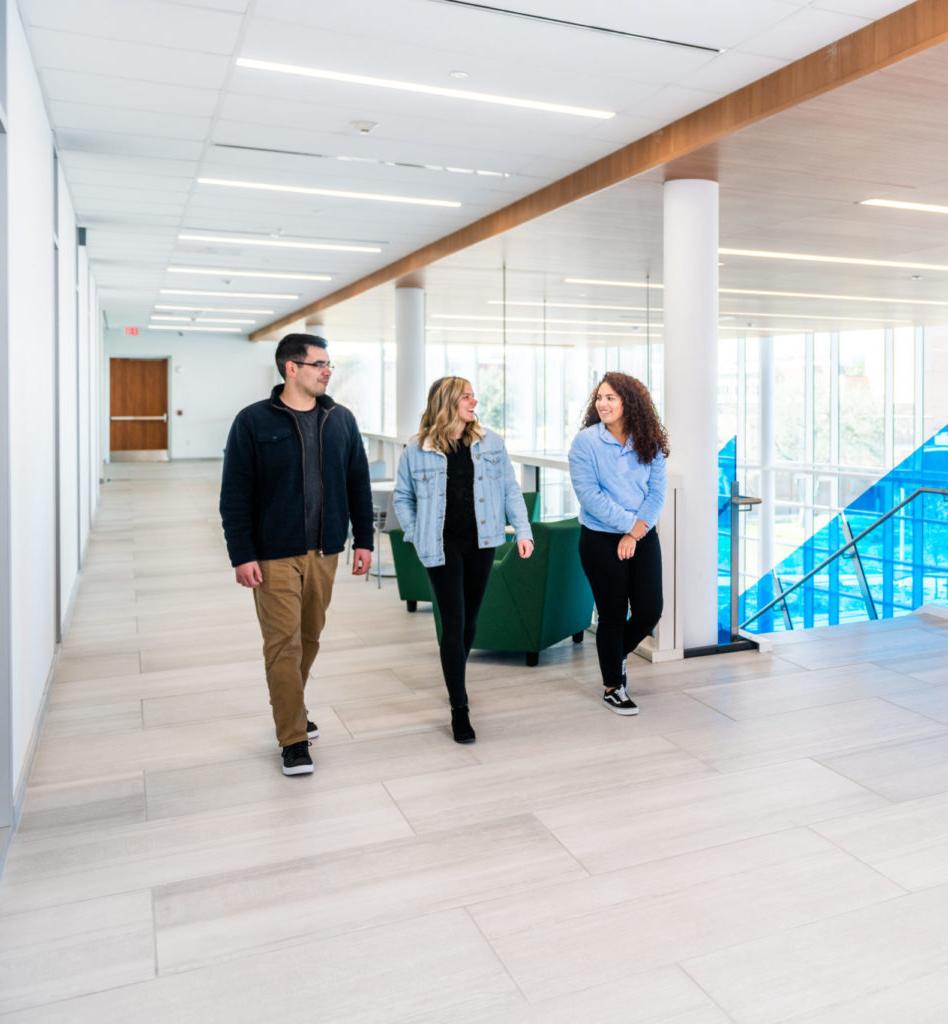 Three students walking and talking inside the new Nursing Health Sciences building on the ETAMU campus.